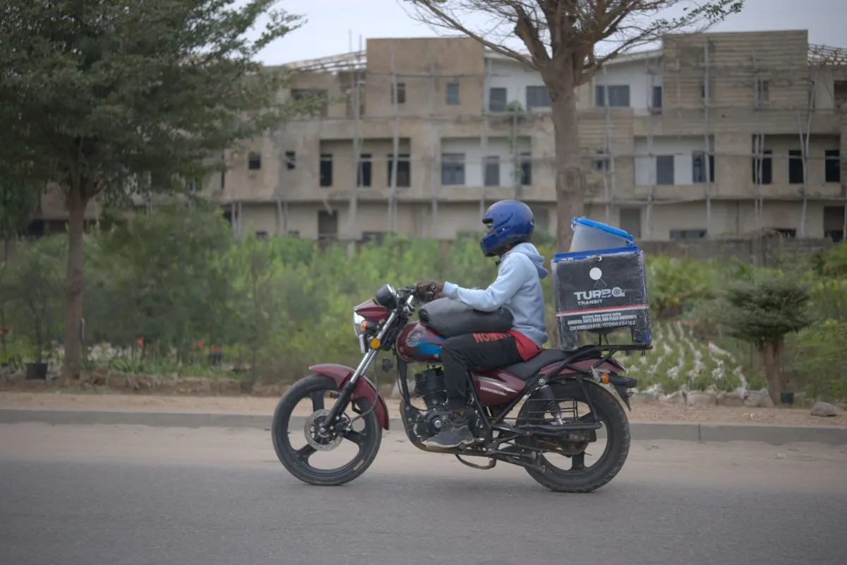Helmeted delivery rider on a motorbike with a delivery box
